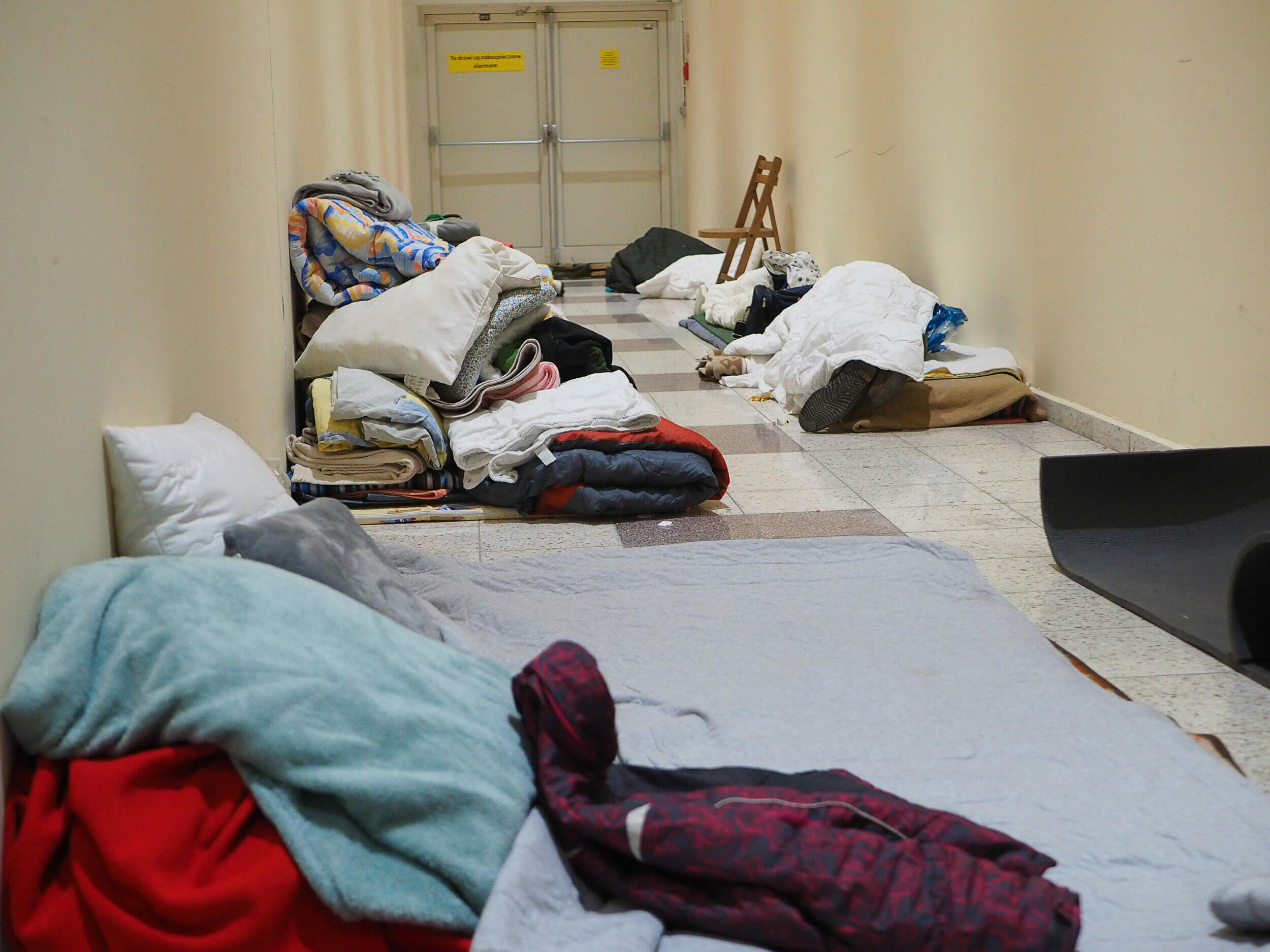 In a hallway in an empty shopping center where people get food and information, one of the arrivals is resting. Mats on the floor serve as emergency sleeping places.