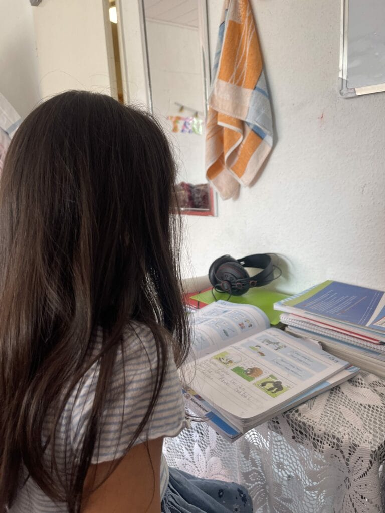 Ein Mädchen sitzt an einem Tisch und sieht sich Bücher an.