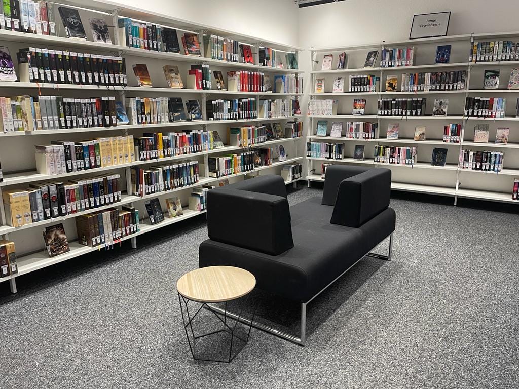 A library with a black couch and bookshelves.